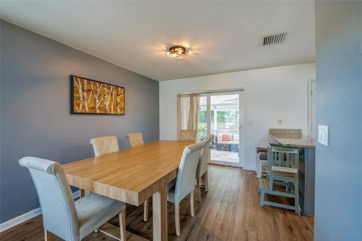 Light-filled dining area featuring LVP flooring, accent wall paint, and sliding glass doors that lead directly out to a covered patio space.
