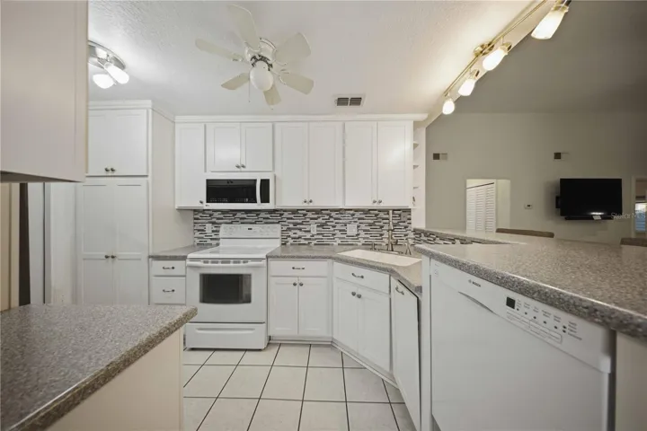 Updated kitchen with raised ceiling, 42" upper cabinets, corian counters, tile backsplash, and on demand instant hot water at sink!