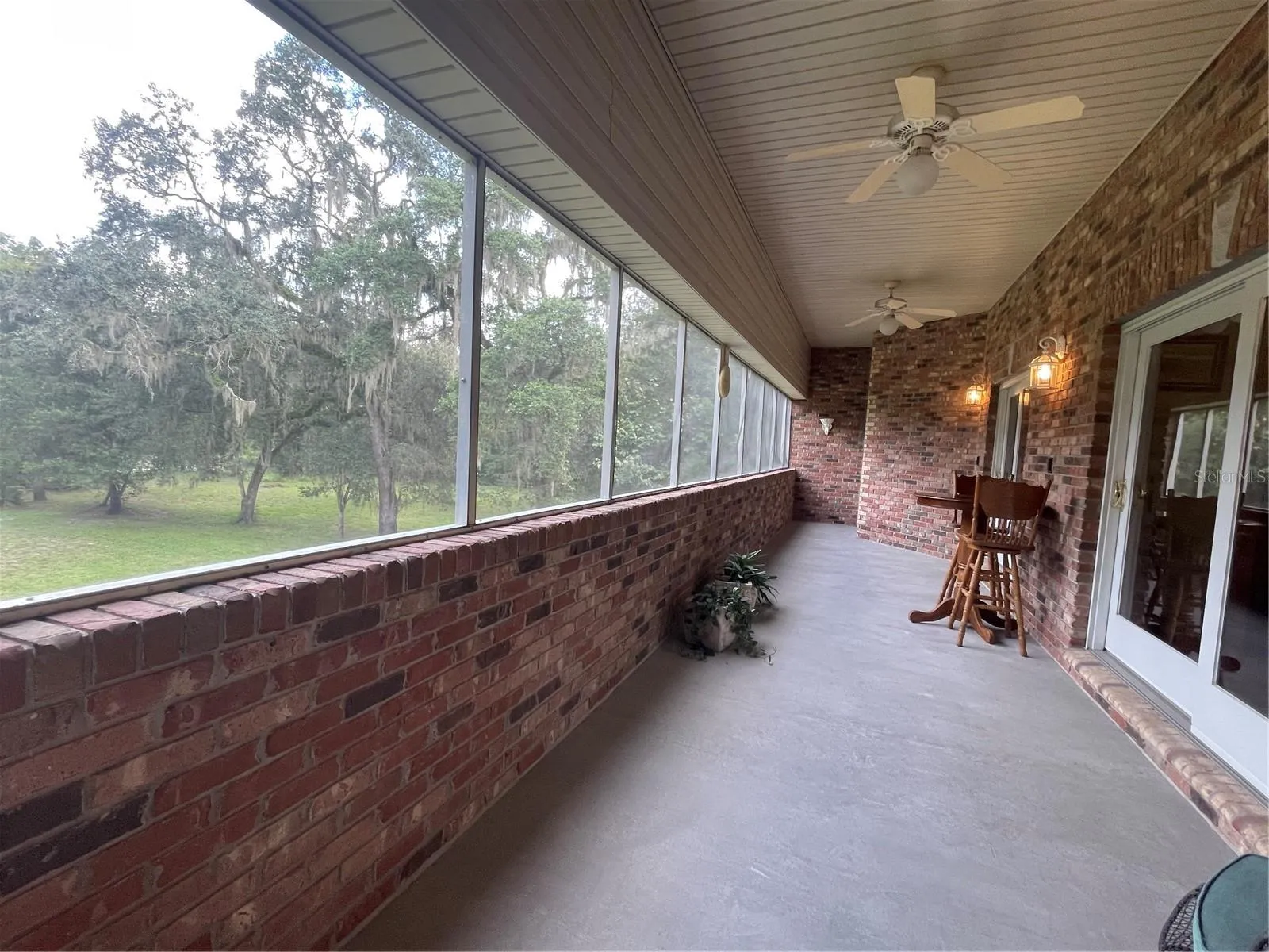 Screened balcony has two sets of sliding glass doors leading to both the primary bedroom and living room