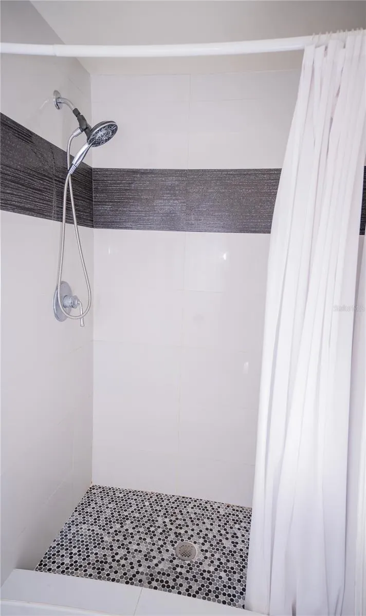 This custom shower features high-end designer tile work, premium fixtures, and luxury tile flooring.