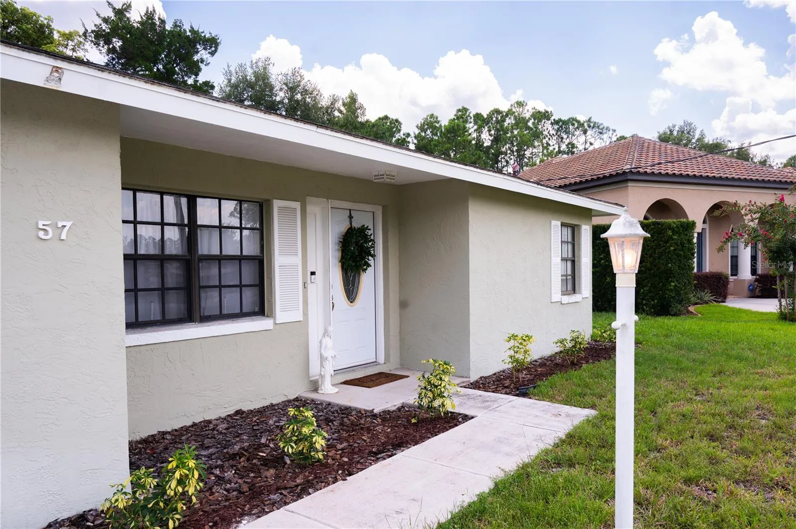 Professional exterior view of the front elevation, showcasing the well-maintained landscaping and inviting entryway.