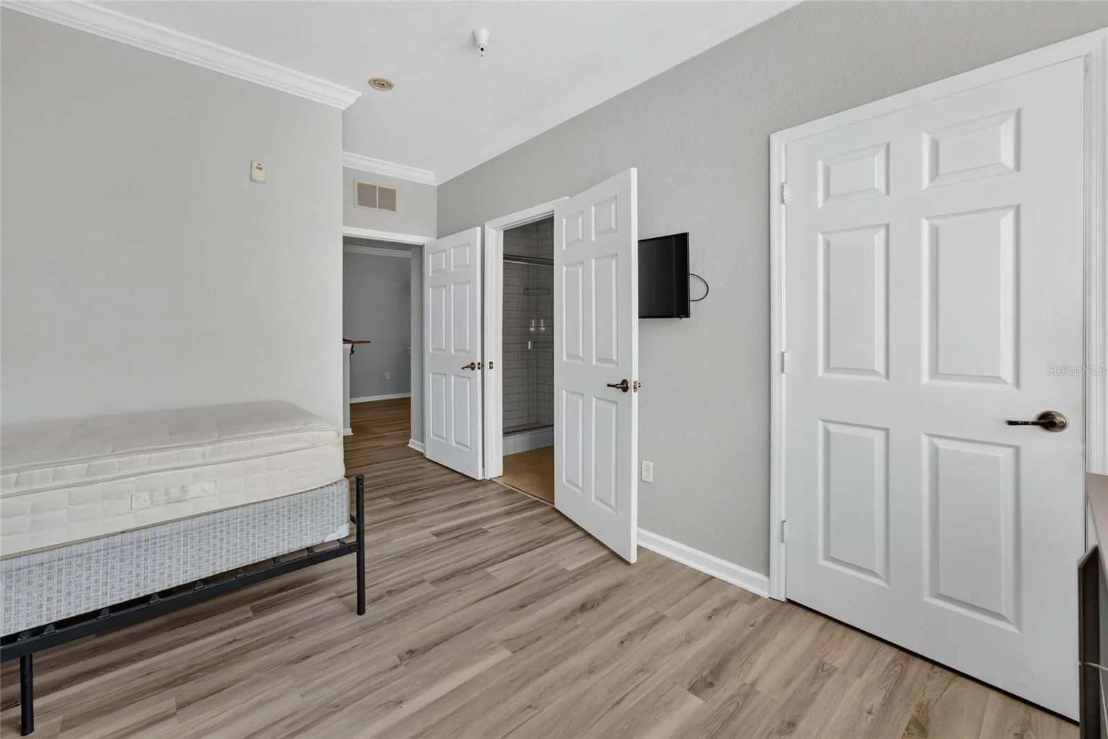 PRIMARY EN SUITE. TV ON WALL. Full bath (left door), and built in closet (door on right).