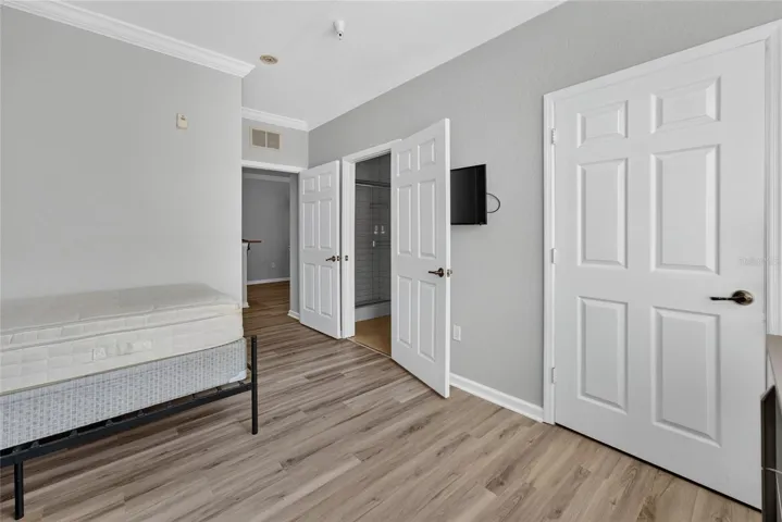 PRIMARY EN SUITE. TV ON WALL. Full bath (left door), and built in closet (door on right).