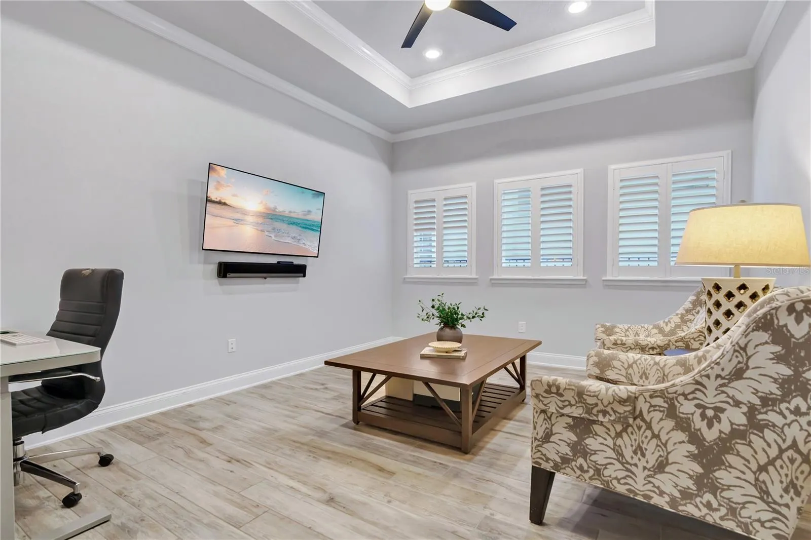Flex room with tray ceiling and plantation shutters, ready for media, work, or guests.