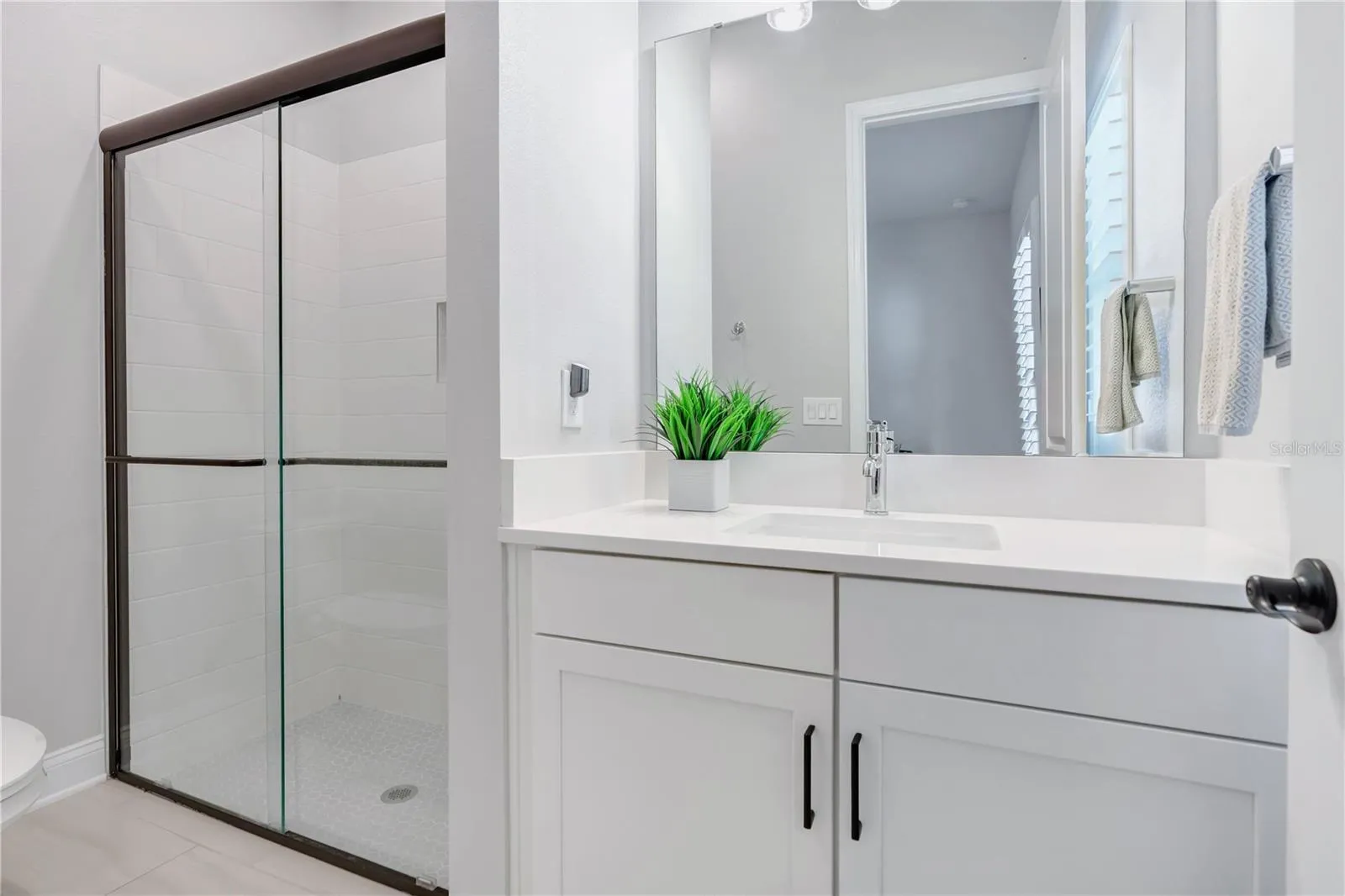 Secondary bath with walk in shower with tile to the ceiling, ceiling mounted rain shower head, and hex mosaic floor.