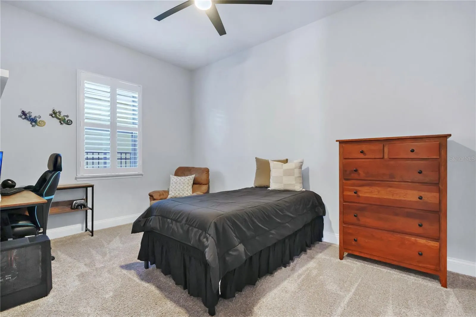Secondary bedroom with ceiling fan, carpet, and a built in closet system.