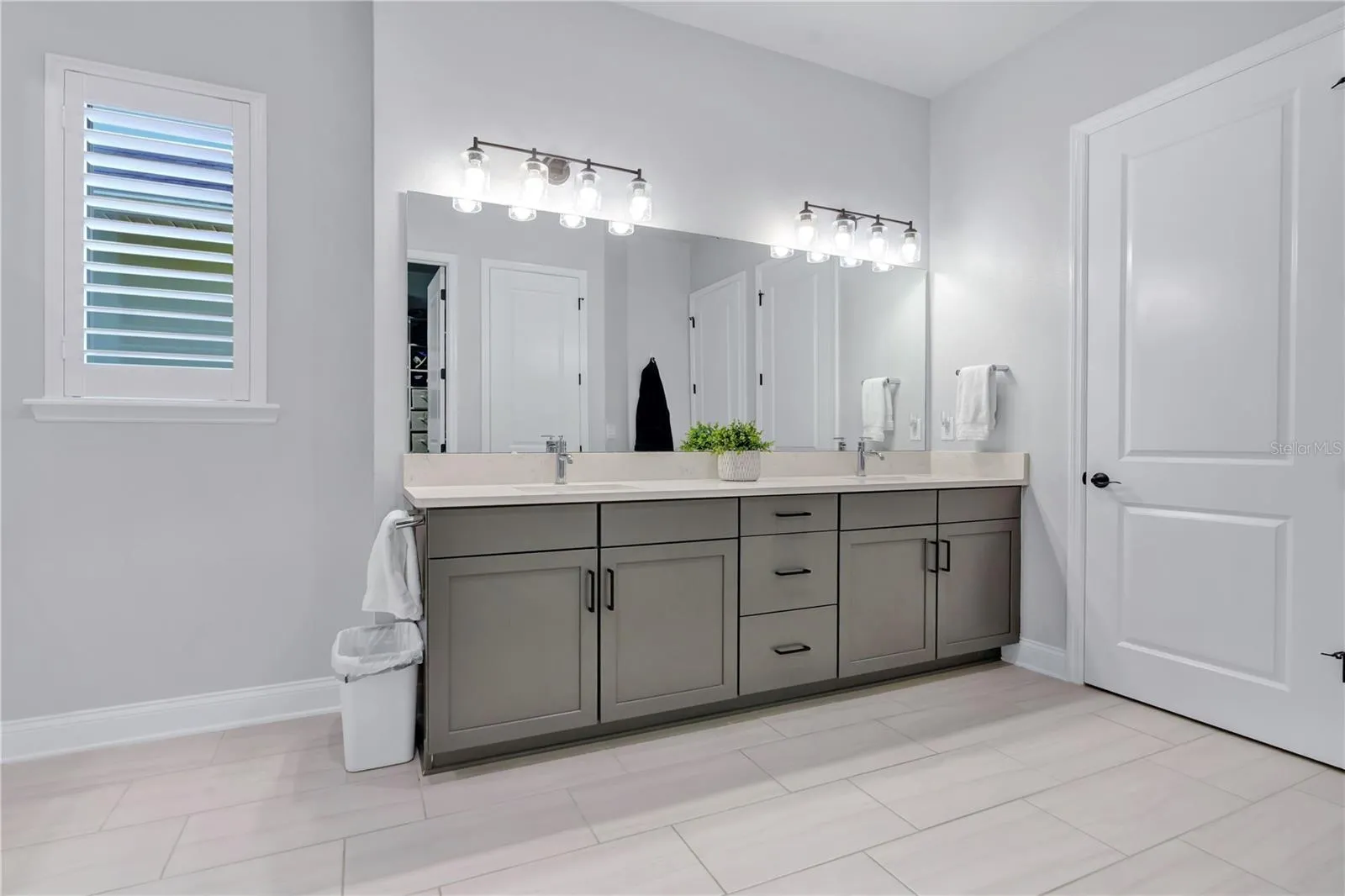 Primary bath vanity with dual sinks, quartz counters, framed mirrors, and modern lighting.