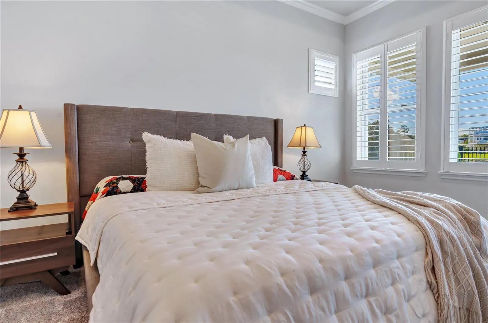 Primary bedroom retreat with room for a king bed and sitting area, plush carpet, and plantation shutters.