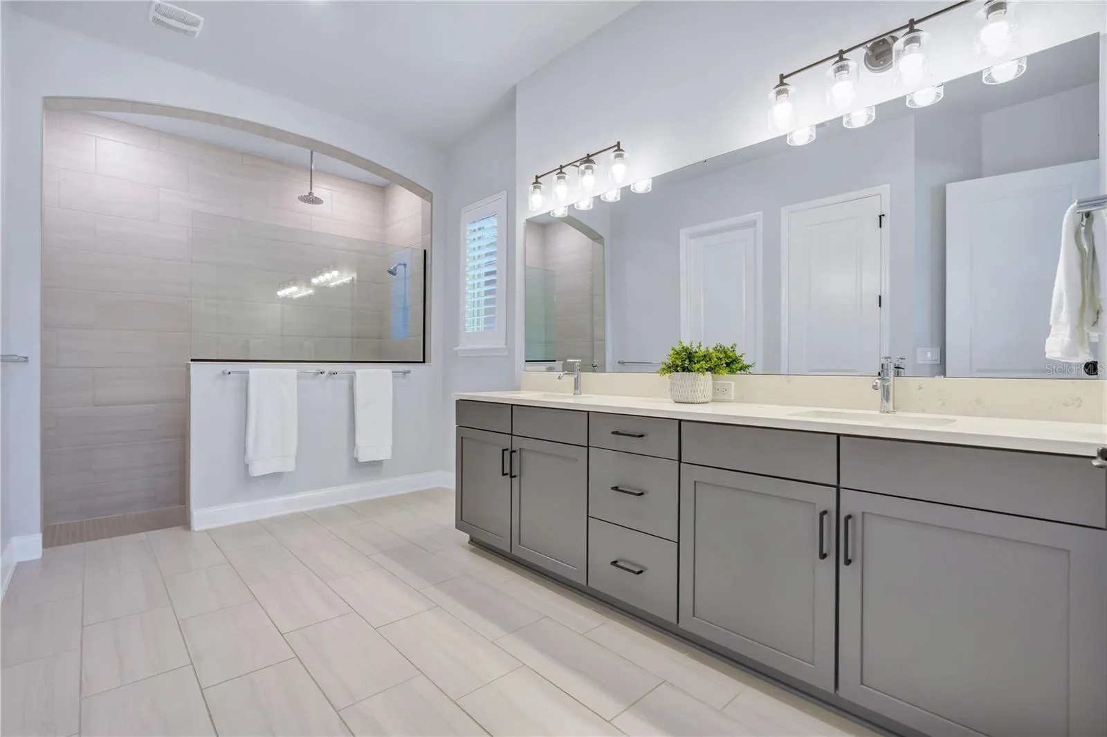 Primary bath with a Carrara Marmi quartz double vanity, extra drawer storage, and a large walk in shower.