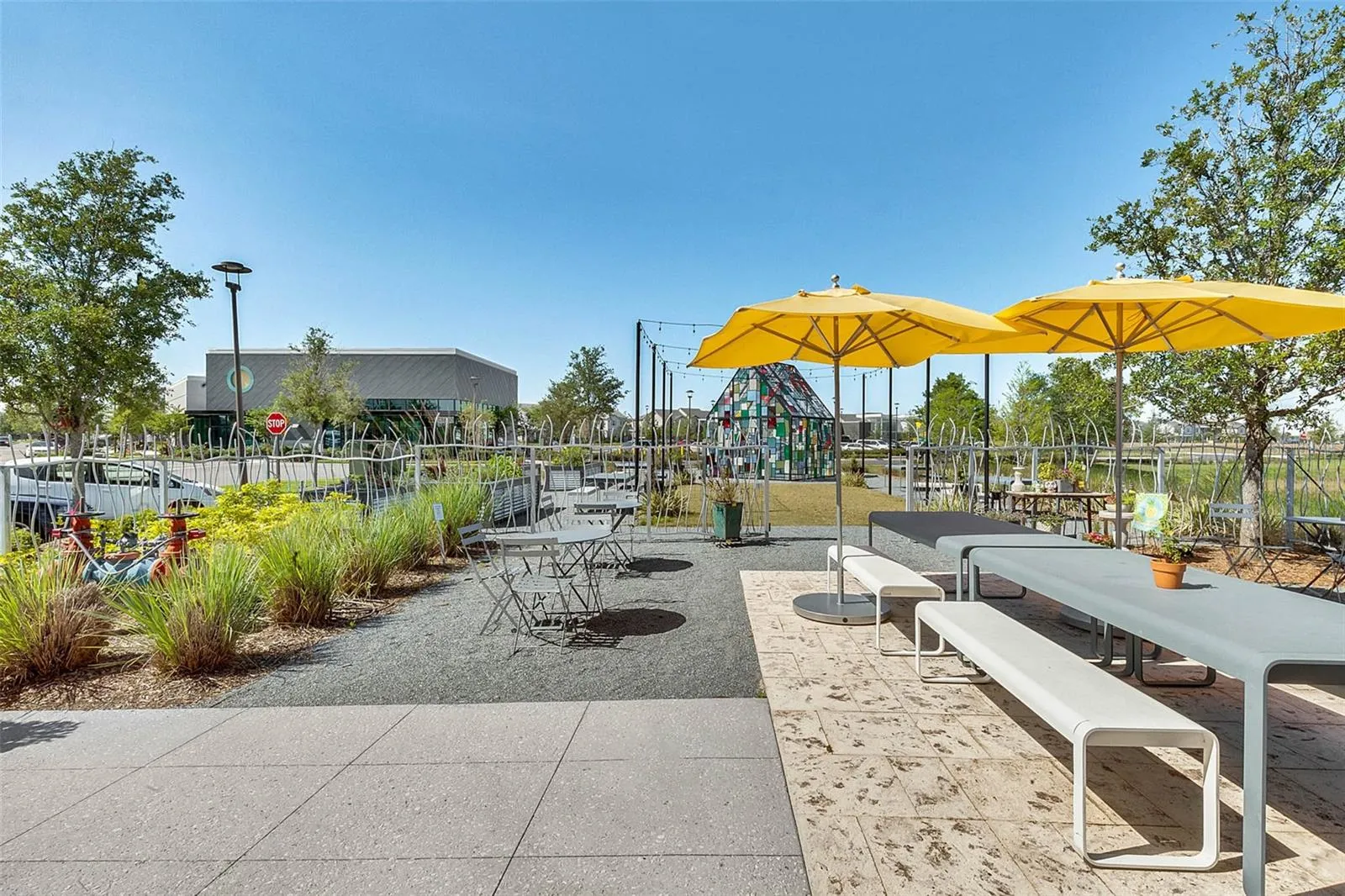 Outdoor gathering space with shaded tables, ideal for relaxing and meeting neighbors in Laureate Park.