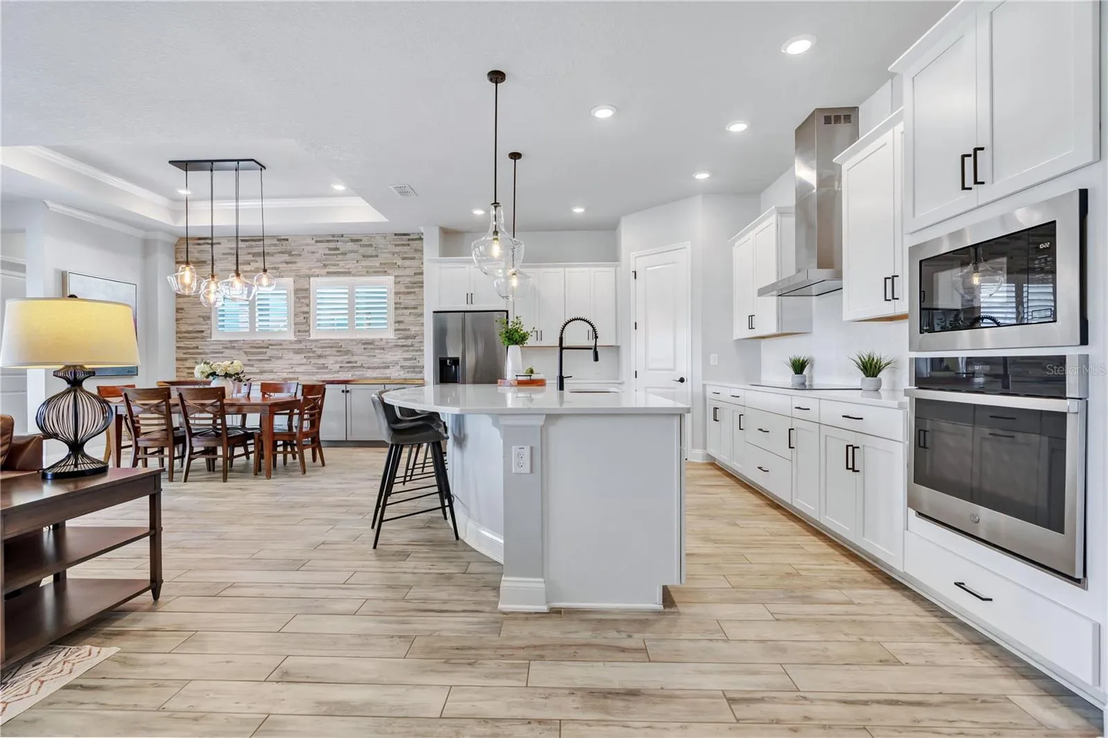Kitchen view from the great room showing the oversized quartz island, 42 inch cabinetry, wall oven, and microwave.