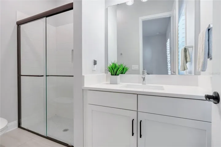 Secondary bath with walk in shower with tile to the ceiling, ceiling mounted rain shower head, and hex mosaic floor.