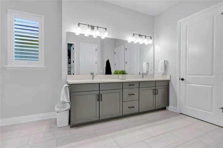Primary bath vanity with dual sinks, quartz counters, framed mirrors, and modern lighting.