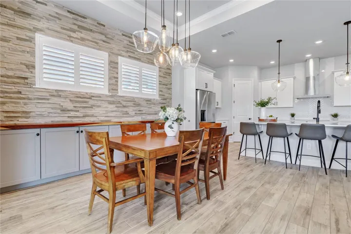 Dining area with a stone accent wall and modern chandelier, steps from the kitchen. Ideal for dinners at home in Lake Nona.