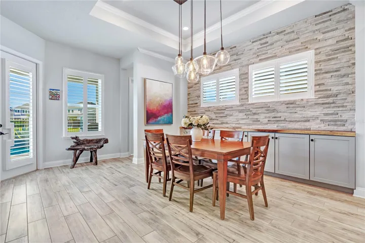 Dining space with natural light and stone accent wall, open to the kitchen and living areas.