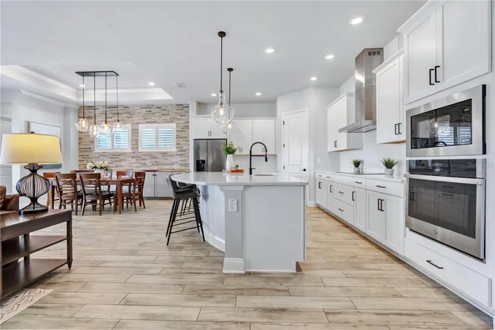 Kitchen view from the great room showing the oversized quartz island, 42 inch cabinetry, wall oven, and microwave.