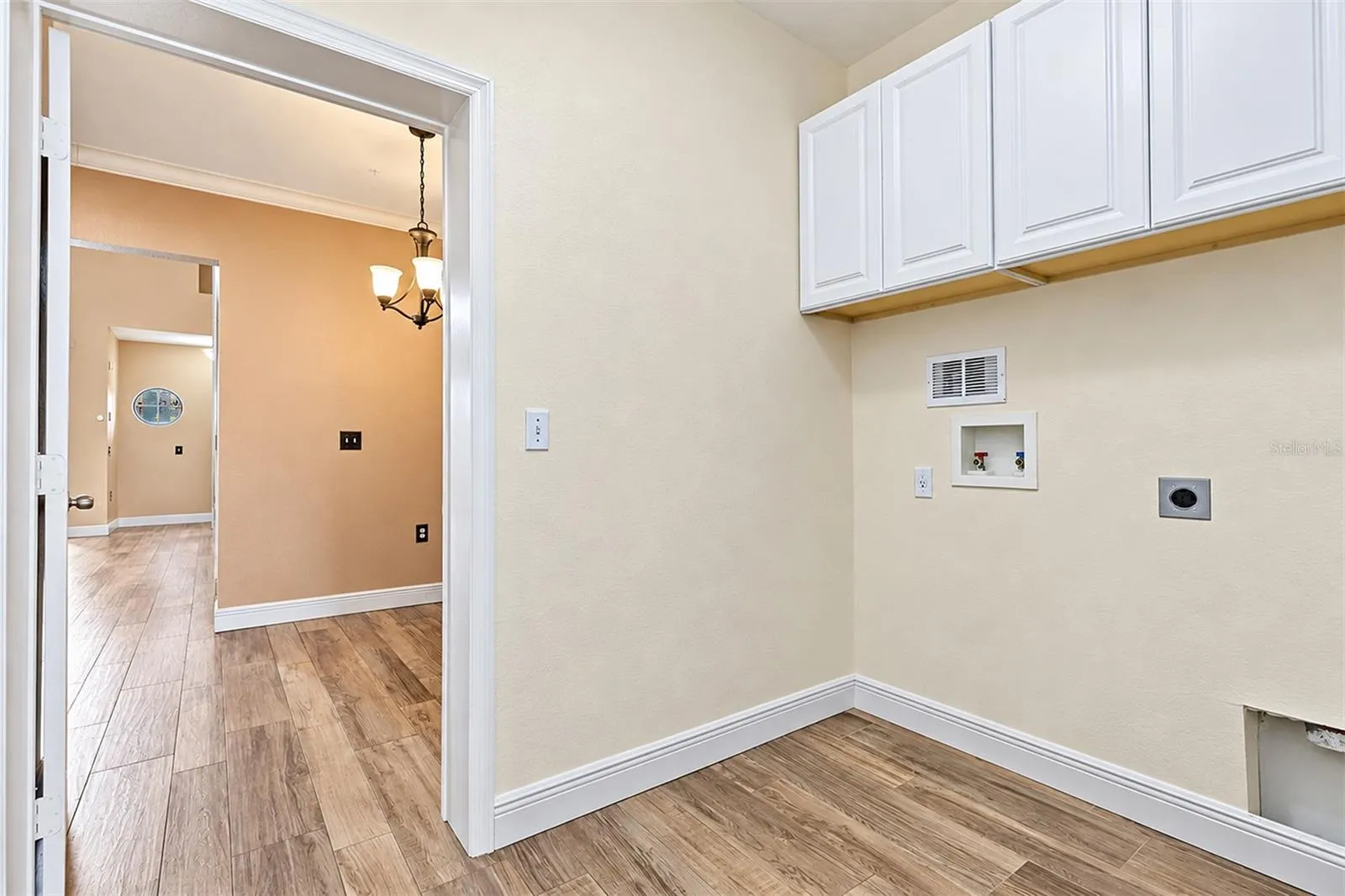 Utility room with cabinets for storage located between kitchen eat in area and garage door entry
