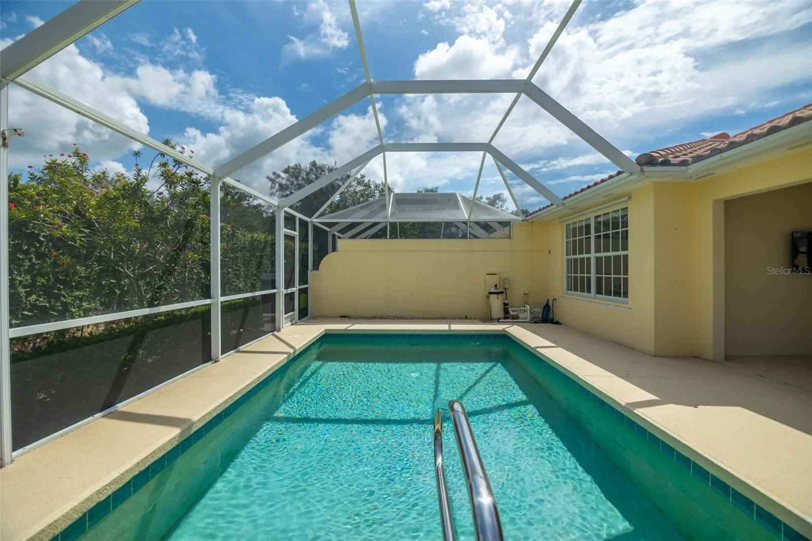 View of pool and pool equipment as well as another screen door at the back of the screen cage.