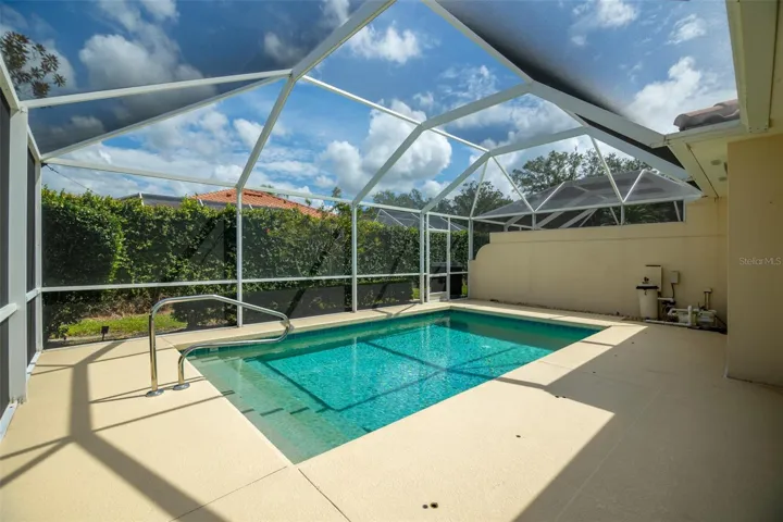 View of pool and pool equipment as well as another screen door at the back of the screen cage.