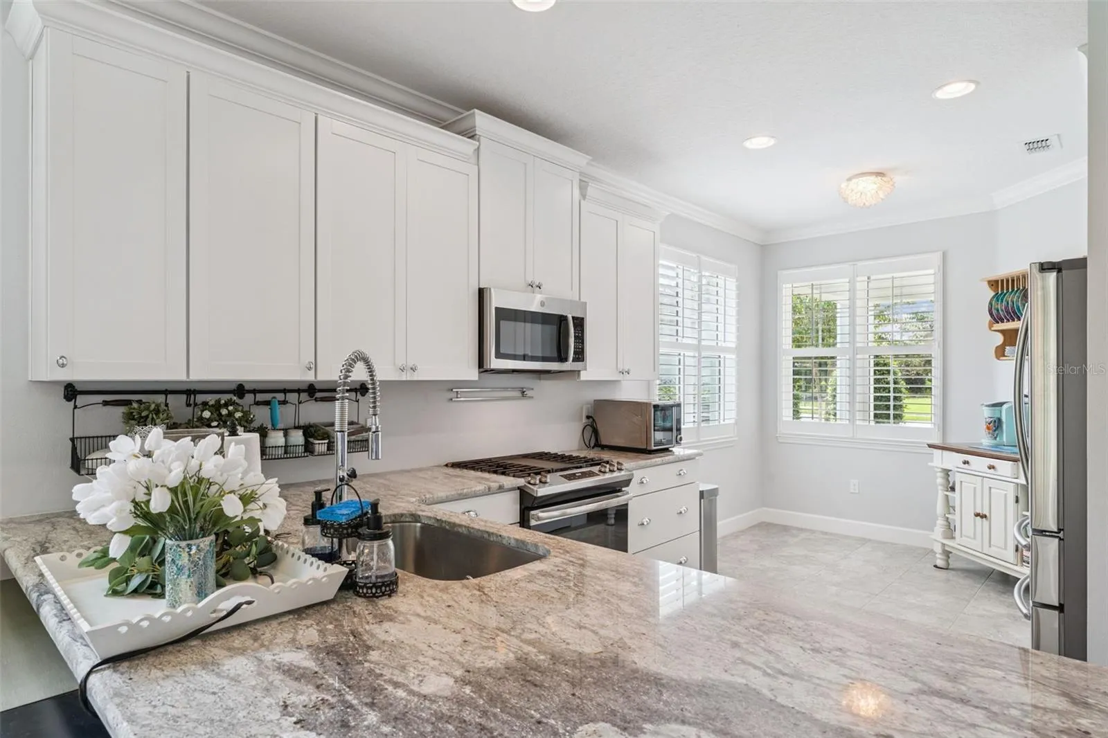 Kitchen w/ a single basin undermount stainless steel sink, 5-burner natural gas range &amp; Plantation style shutters