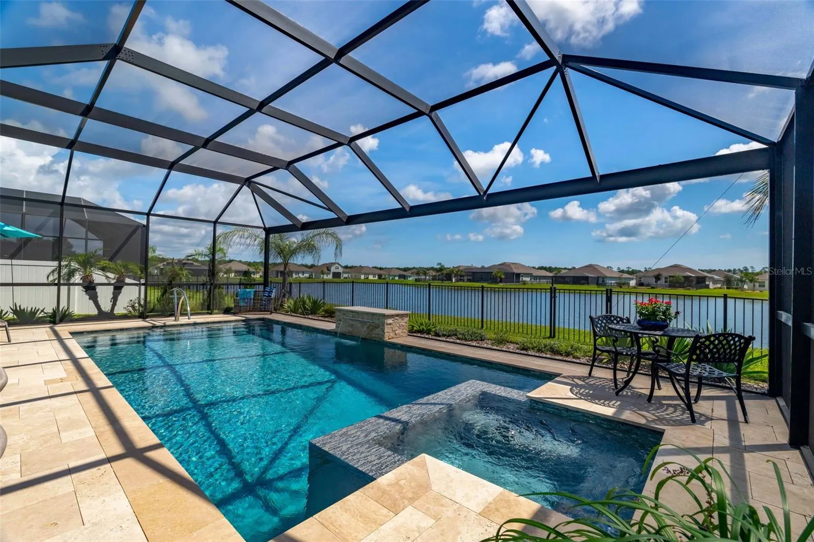 Fully screened and heated in-ground pool with travertine deck, mosaic tiles, and waterfall.