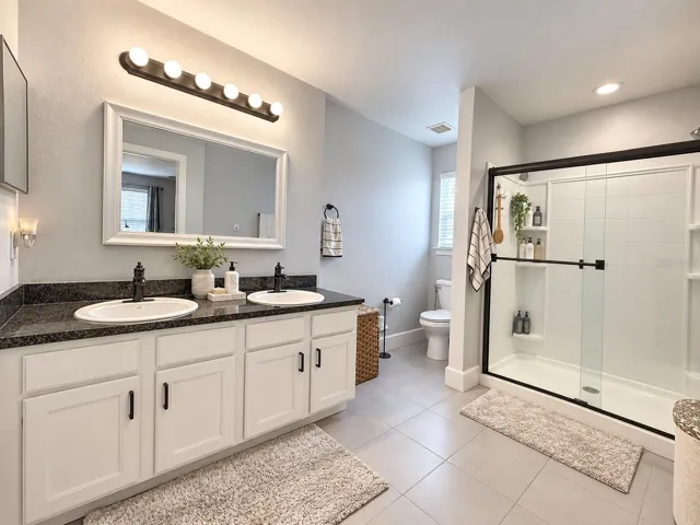 Primary bathroom with dual sinks and glass-enclosed shower.