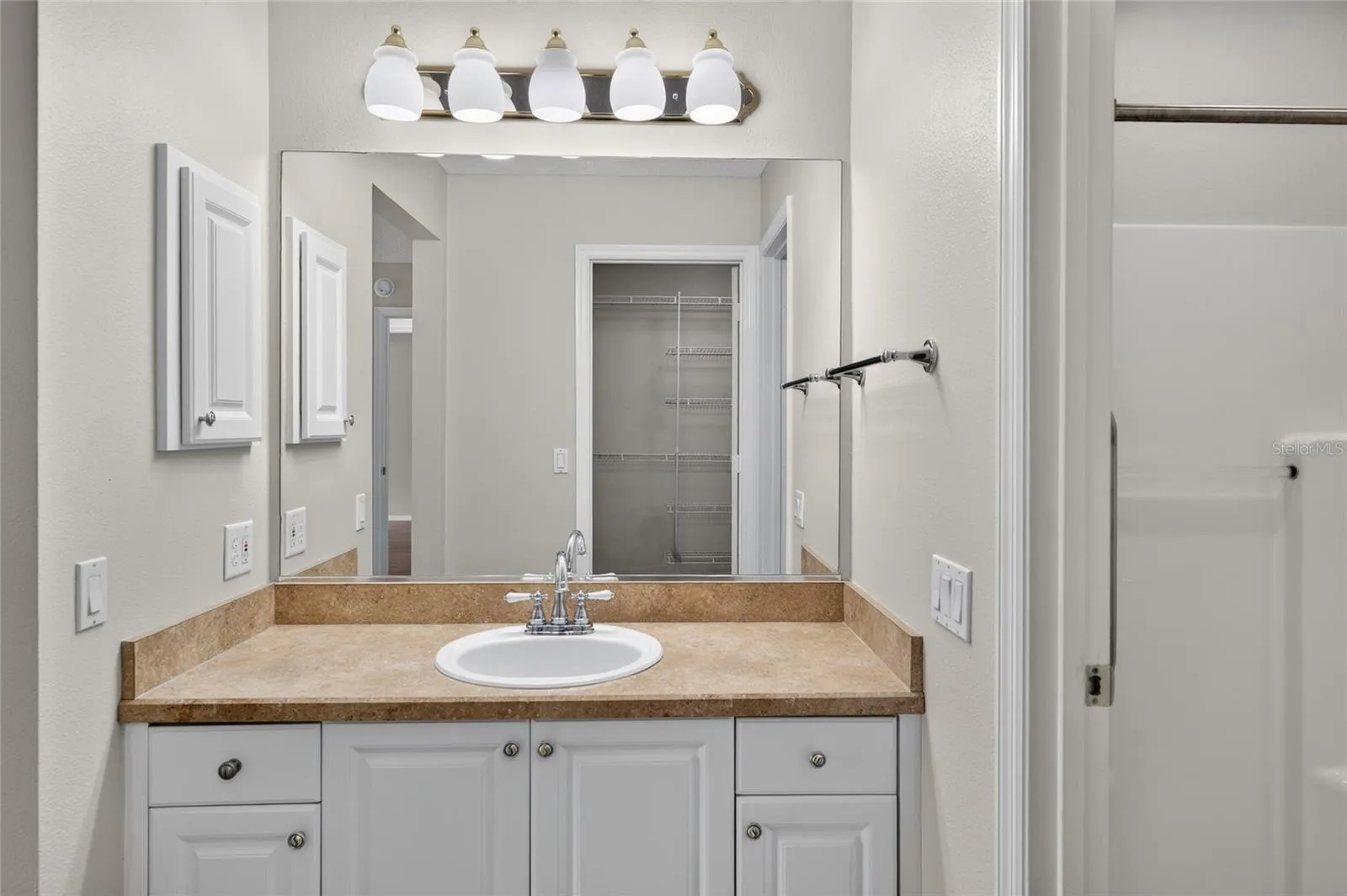 PRIMARY ENSUITE BATHROOM - View across the vanity toward the walk-in closet doorway (reflected in the mirror). A glimpse of the WALK-IN SHOWER is visible on R.