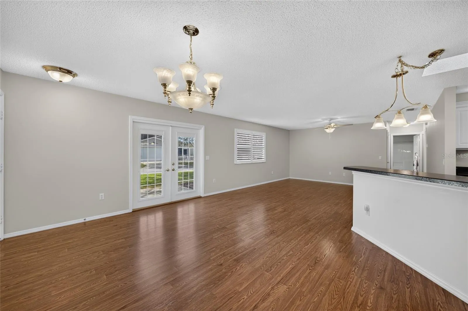 Overview of DINING / KITCHEN/LIVING ROOM - A dining chandelier, breakfast-bar pendant and a new ceiling fan w/ alabaster-white bowl coordinate the lighting across the connected spaces.