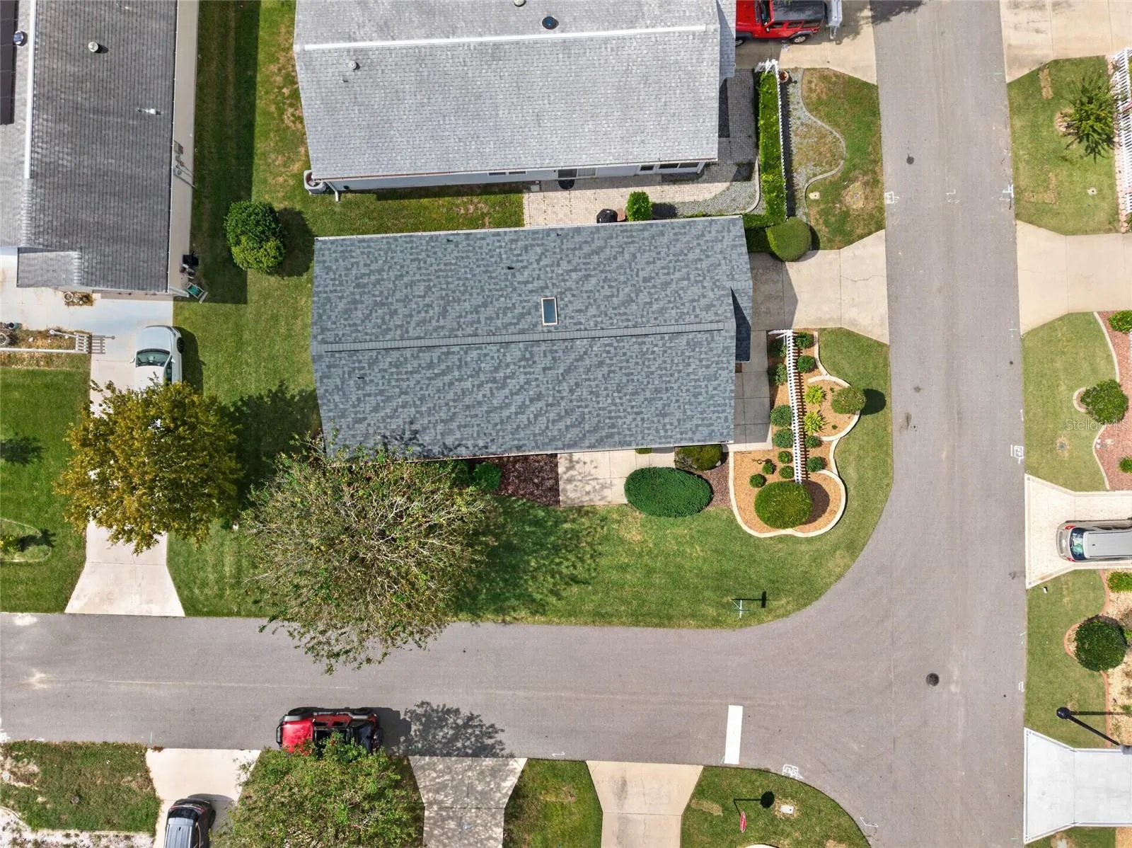 OVERHEAD AERIAL - Top-down view of the ARCH SHINGLE ROOF (2025) and the villa's footprint on a corner lot between the adjoining streets.