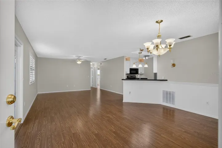 View from FRONT DOOR - Shows DINING ROOM (front R), KITCHEN w/ breakfast bar (center R), LIVING ROOM (back L), and HALLWAY (back R) to rear of villa.