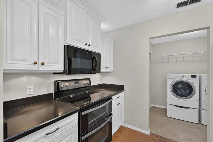 KITCHEN -View of a DOUBLE OVEN and OTC MICROWAVE HOOD which are located on the south wall of the kitchen. INDOOR LAUNDRY is visible on R.