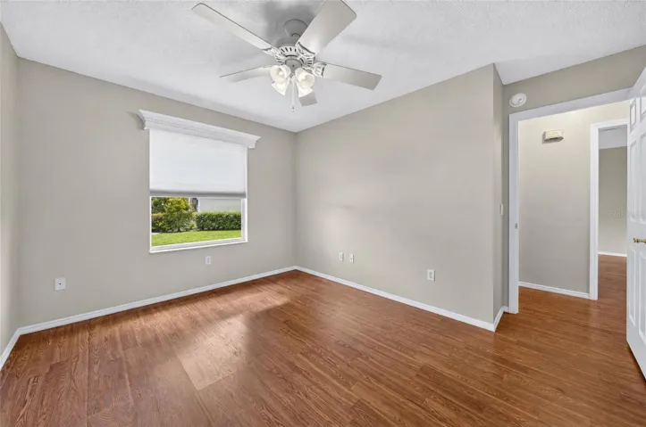 Another view of BEDROOM #2 - Shows white wooden window cornice and a ceiling fan with light. Note doorway (R) that shows connection to HALLWAY and main living area.