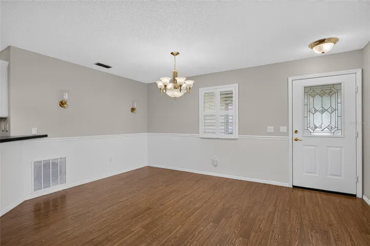 Close up view of DINING AREA - Alternate angle showing the chair rail and back of FRONT DOOR w/ half-lite decorative glass insert.