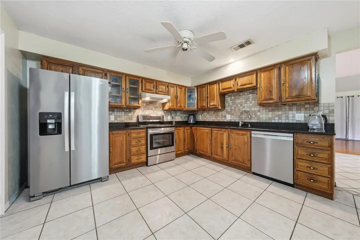 KITCHEN WITH STAINLESS APPLIANCES, SOLID WOOD CABINETS + GRANITE