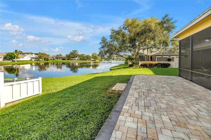 The elevated paver patio at the rear of the property overlooks a scenic grassy knoll and provides an expansive view of the lake, which serves as a natural habitat for various tropical birds.