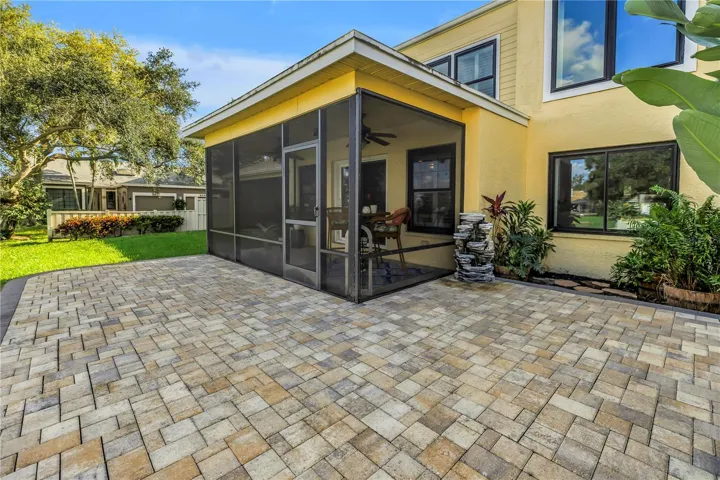 This screened, covered patio features a raised paver deck, providing an ideal space for an outdoor kitchen or grill.  Adirondacks ?!