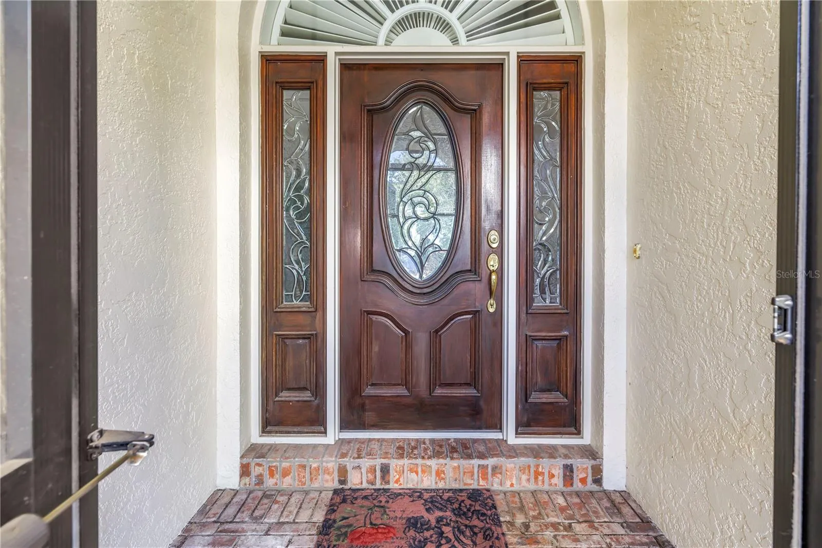 Beautiful front door featuring solid wood construction and elegant leaded glass. This upscale entry is also screened, allowing for refreshing natural breezes.