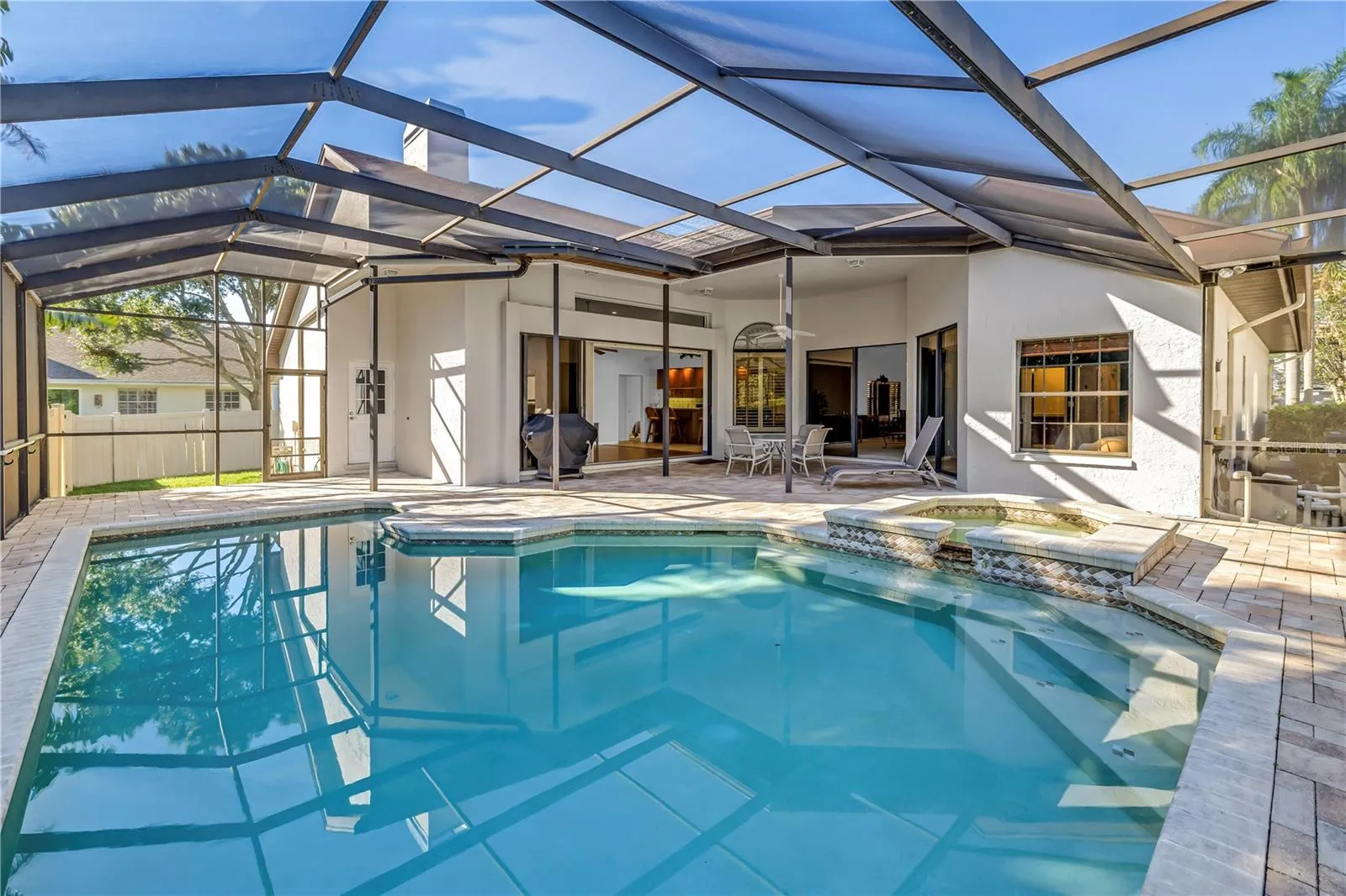 This backyard oasis features in-pool seating and expansive open space under the screened lanai. The design seamlessly integrates the interior living area with the outdoors while maintaining complete privacy.