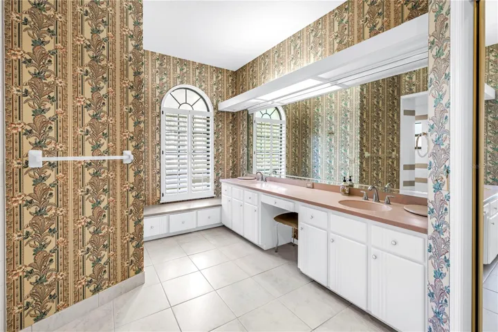 Current Photo of Primary Bath with long dual Vanity and dressing table.  Shower is behind wall with towel bar.