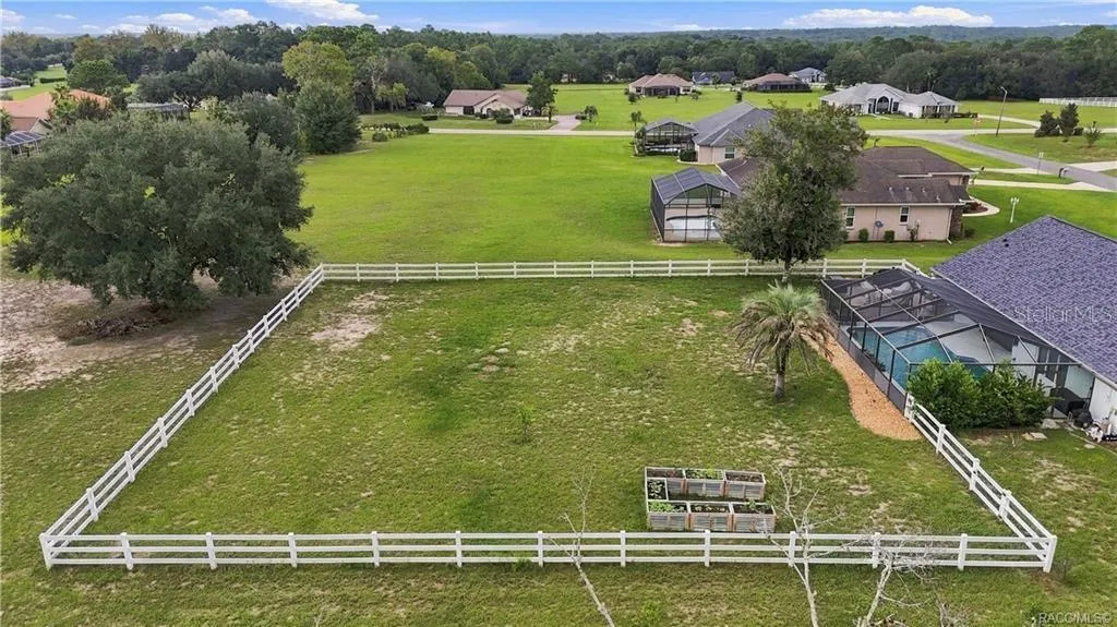 Aerial Backyard View – Take in the spacious WHITE RAIL-FENCED BACKYARD, raised garden beds & SCREEN-ENCLOSED POOL, all surrounded by beautiful green space. A wonderful setting for enjoying the outdoors!