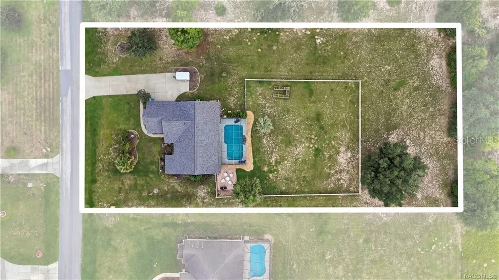 Bird's-eye view showcasing the spacious 1.02-acre homesite, screened-in pool, white rail-fenced backyard & outdoor living areas.