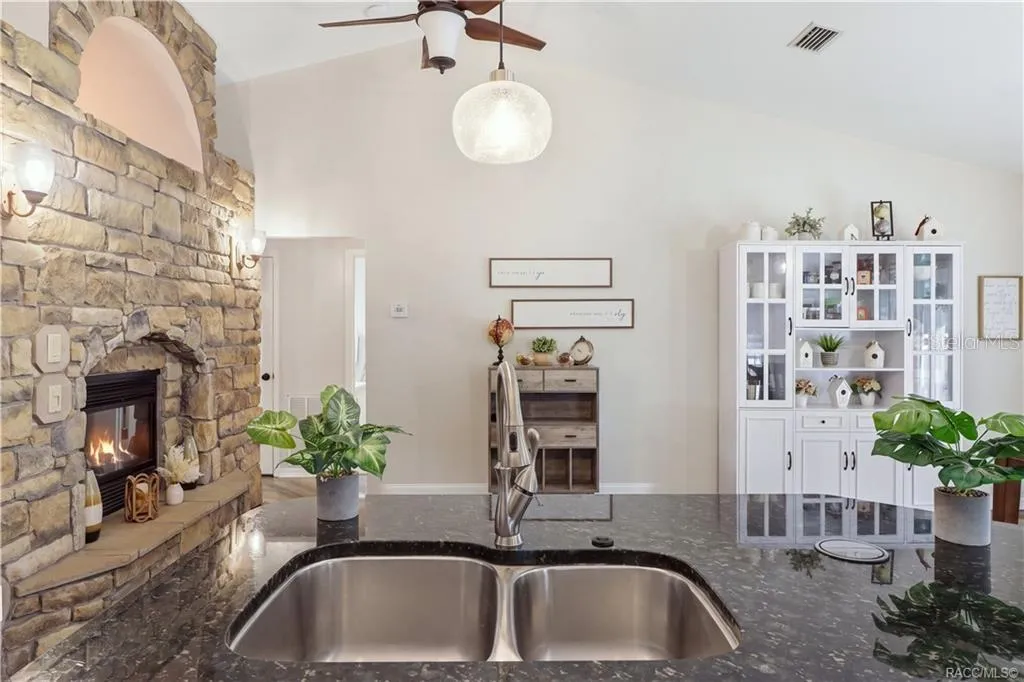 KITCHEN & FIREPLACE VIEWOpen kitchen showcasing the granite island, vaulted ceilings, stone-accented fireplace & adjoining dining area.