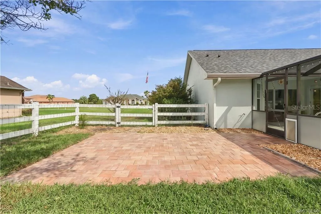Outdoor Paver Patio – Open-air paver patio beside the pool enclosure, providing an additional spot for outdoor seating or entertaining.