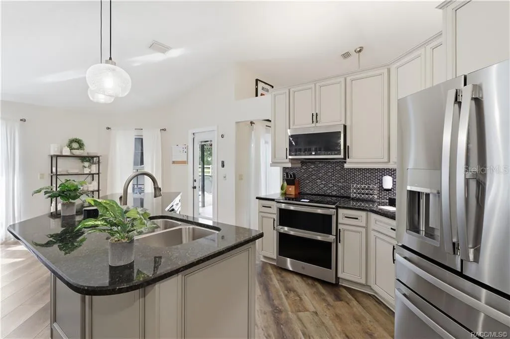 KITCHEN– Updated kitchen featuring NEWER STAINLESS STEEL APPLIANCES to include double oven, light-colored cabinetry, granite countertops & decorative ceramic tile backsplash.
