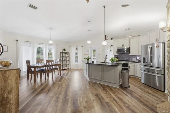 OPEN KITCHEN & DINING AREA- Beautiful open-concept kitchen & dining area featuring vaulted ceilings, granite countertops, center island & newer luxury vinyl flooring.