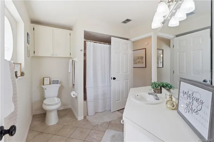 Guest Bathroom – Clean, inviting guest bathroom featuring a tub/shower combination, tile flooring, vanity & additional storage cabinetry.