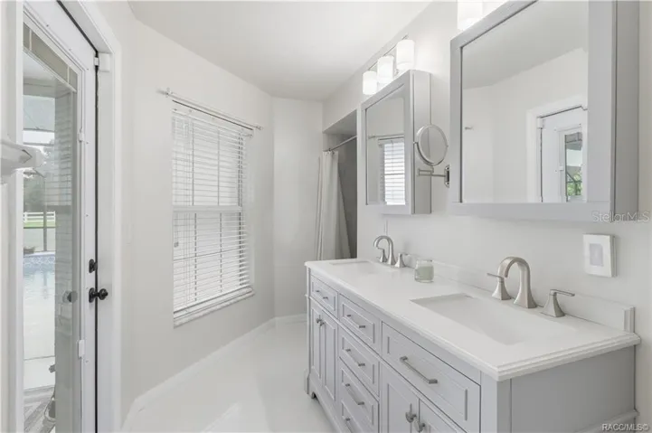 Primary Bathroom – Light & bright primary bathroom featuring a double-sink vanity, updated cabinetry, generous countertop space & direct access to the screened pool area.
