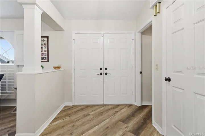WELCOMING FOYER- Bright entry foyer featuring double doors, newer luxury vinyl flooring & an open transition into the main living areas.