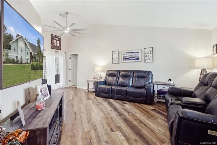 LIVING ROOM – VAULTED CEILING- Spacious living area featuring a vaulted ceiling, newer luxury vinyl flooring & ceiling fan.