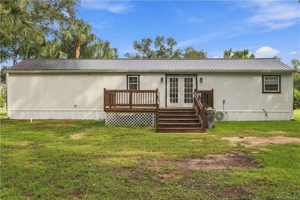 Rear Exterior – Attractive rear elevation featuring the METAL ROOF, French doors, wooden deck w/steps &amp; a MINI-SPLIT HEATING &amp; COOLING SYSTEM.